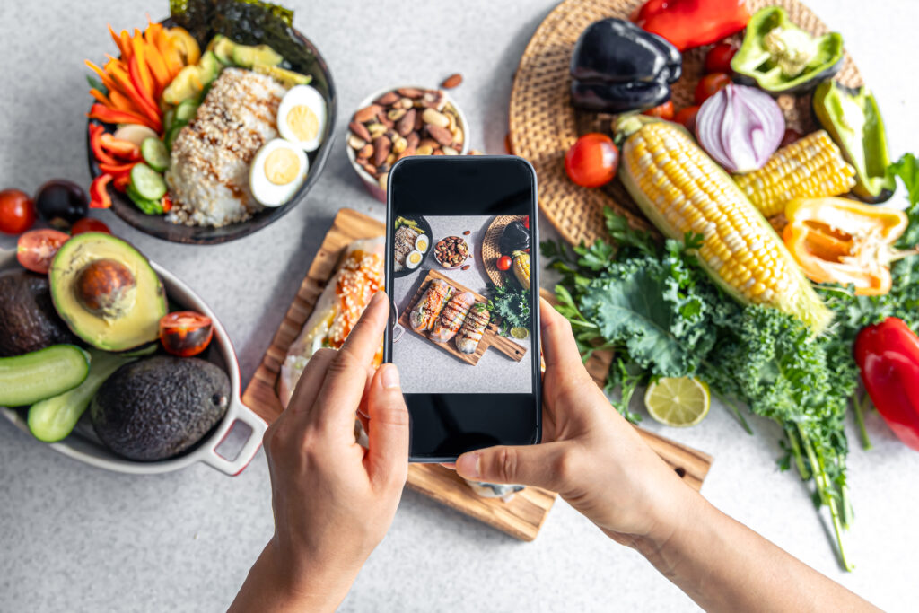 A woman takes a photo of spring rolls on a smartphone, a blogger takes photos of Asian food.